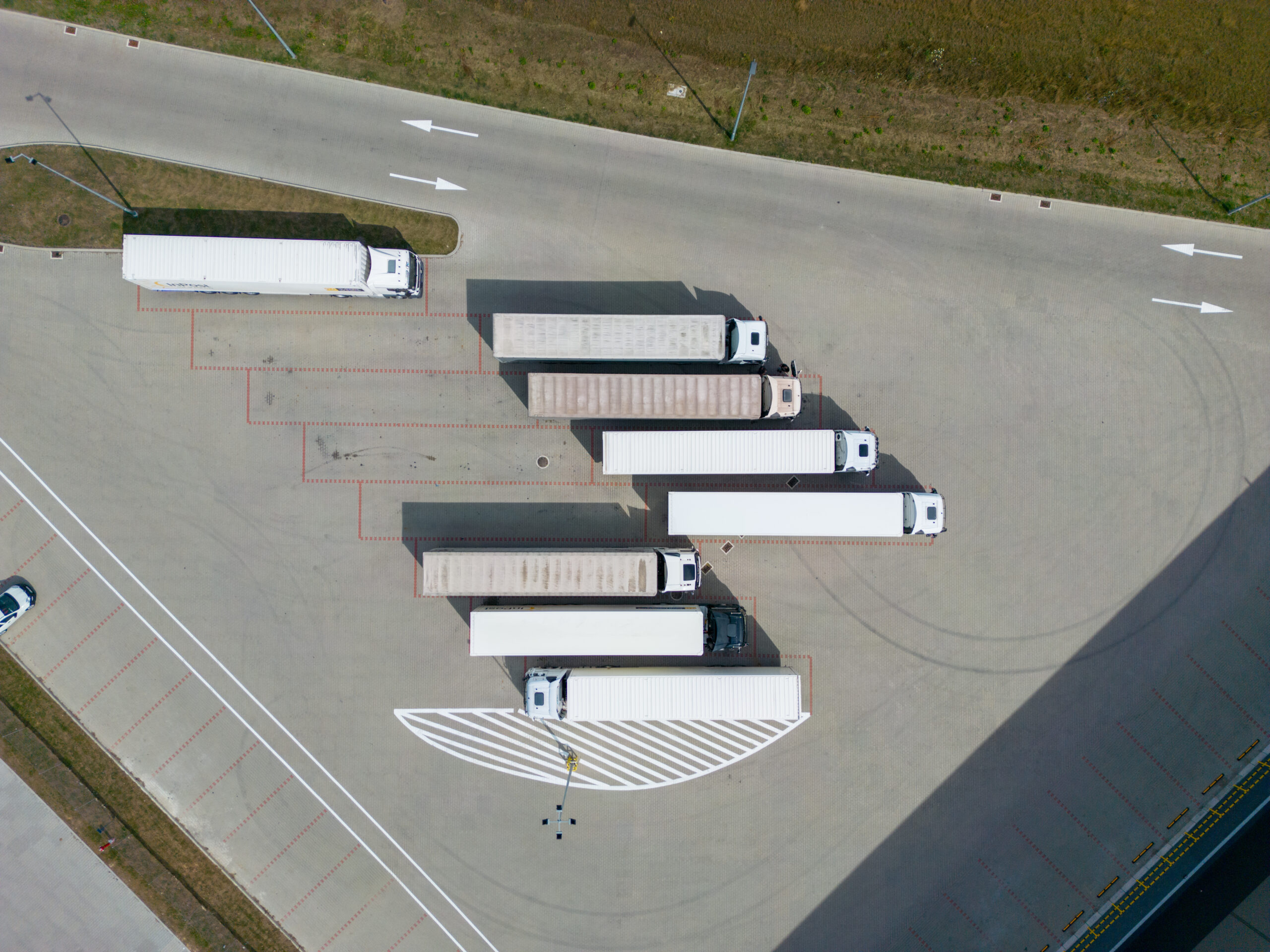 aerial drone view of parking with trucks and trailers Vista aérea de vários caminhões estacionados em uma ampla área de manobra.